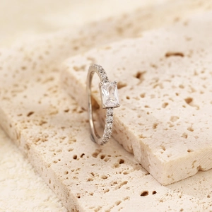 Macro view of a silver s925 ring with a rectangular zircon stone on porous stone texture