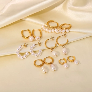 Close-up of assorted 18K gold plated earrings with white pearls on yellow silk background