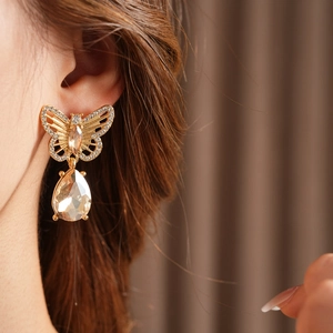 Détail de boucles d'oreilles papillon dorées vintage avec gouttes de cristal brillant
