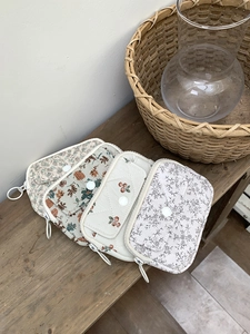 Close-up of four floral quilted fabric card holders with ring zippers on a wooden bench
