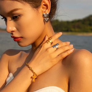 Close-up of heart-shaped double earrings and gold cross jewelry worn by a model