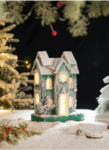 Detail of glowing green Christmas cottage with LED light and snow on festive background