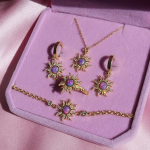 Detailed close-up of a gold sunburst jewelry set with opal stones in a pink velvet box