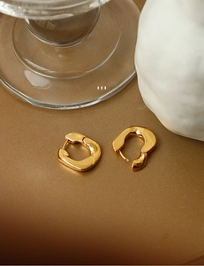 Macro detail of minimalist 18K gold plated brass hoop earrings with irregular organic shape