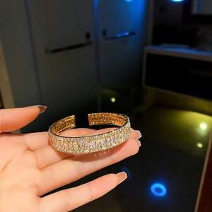 Bracelet manchette géométrique doré avec pierres en zircon porté sur le poignet