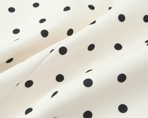 Gros plan sur tissu blanc à pois montrant une texture en mousseline lisse et des drapés
