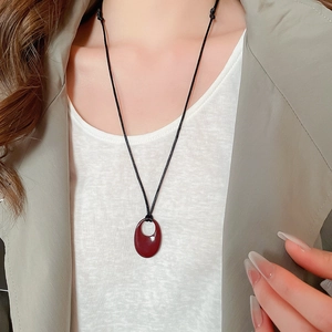 Détail d'un collier pendentif ovale rouge foncé avec cordon noir sur un mannequin