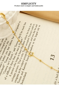Macro shot of gold star bracelet with zirconia flower pendant on vintage book pages