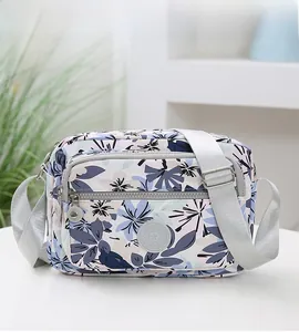 Detail of floral crossbody bag showing water-resistant fabric and zip pockets