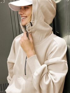 Close-up of beige oversized quarter-zip hoodie showing cotton fleece texture and elastic cuffs
