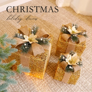 Three-piece set of golden glitter Christmas gift boxes with burlap bows and pine decorations