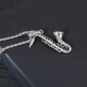 Detailed view of polished stainless steel saxophone pendant with intricate instrument keys
