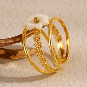 Macro view of a triple-layered 18K gold-plated ring with a white pearl shell flower