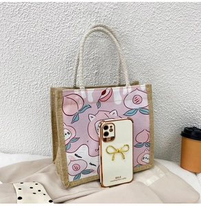 Detail of jute canvas tote bag with pink cat and peach print showing scale with phone