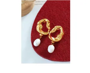 Macro detail of 18K gold-plated irregular lava earrings with white freshwater pearl drops