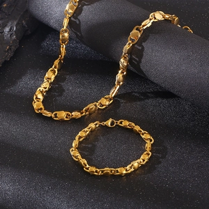 Detailed view of golden titanium steel chain necklace and bracelet set on black surface