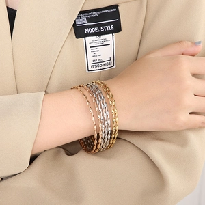 Dreiteiliges gedrehtes Armreif-Set in Gold, Roségold und Silber am Handgelenk eines Models