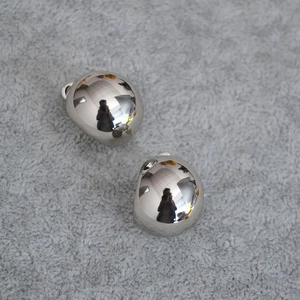 Detailed view of glossy silver irregular pebble earrings on a soft grey fabric