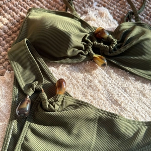 Close-up of olive green ribbed bikini with amber resin beads and textured fabric details