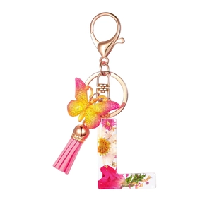Detail of letter L resin keychain with real dried flowers, butterfly and pink tassel