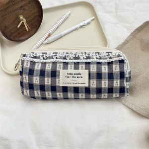 Detail of checkered canvas pencil case with cherry print and white lace trim detail