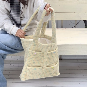 Detail of colorful plush tote bag featuring four pockets and decorative buttons