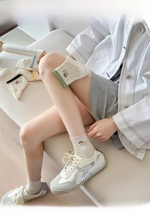 Close-up of cream knit socks featuring colorful ribbed cuffs and cute cartoon puppy embroidery