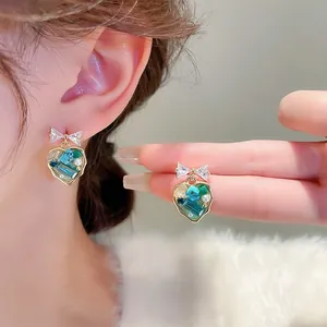 Detail of heart drop earrings featuring bow design and colorful gradient crystals