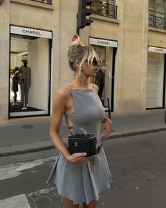 Détail d'une robe grise plissée dos nu et d'un sac matelassé noir dans la rue