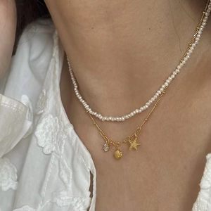 Close-up of double layer necklace featuring pearls, golden starfish and shell pendants
