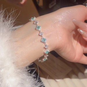 Detail of silver chain bracelet with green gems and white zircons on wrist