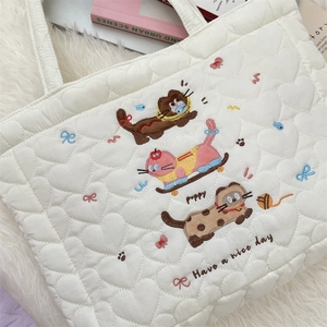 Close-up of heart-shaped quilting and cute puppy embroidery on a white quilted tote bag