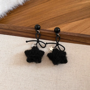 Close-up of black velvet star earrings with ribbon bows and silver star accents