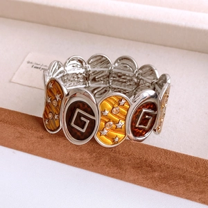 Detailed macro view of an oval enamel vintage elastic bracelet with star and G patterns