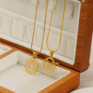 Golden zodiac pendant necklace featuring Libra and Taurus signs in a wooden gift box