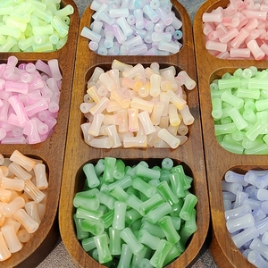 Bamboo-shaped gradient glass beads in a wooden tray for DIY hair accessories and jewelry