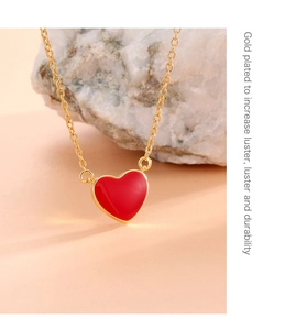 Close-up of gold-plated red heart pendant on a natural stone showing high luster and shine