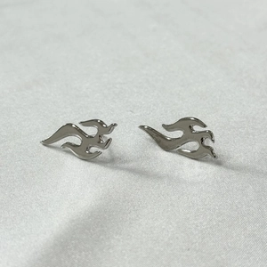 Polished silver stainless steel flame design stud earrings set on a white textured background
