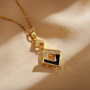 Close-up of geometric gold necklace with white zircons and black enamel pendant