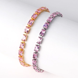 Close-up of gold and silver bracelets with pink square zircon on white pillar stand