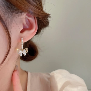 Eleganti orecchini a fiocco dorati con perle e strass indossati dalla modella