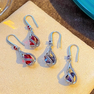 Close-up of teardrop zircon earrings with red and purple crystals in silver swirl setting