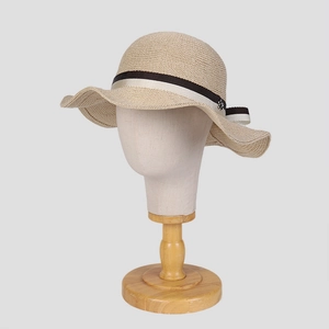 Detail of elegant knit sun hat featuring wavy brim and black ribbon with silver buckle