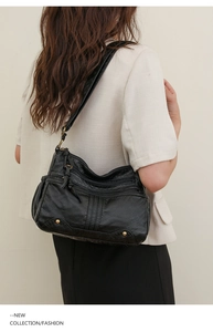 Détail d'un sac à bandoulière en cuir lavé noir avec rivets dorés porté par un mannequin