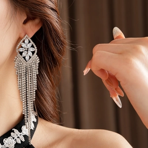 Detail of silver rhumboid stud earring with long sparkling rhinestone tassels on ear