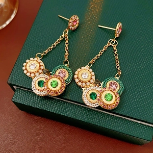 Vue détaillée de boucles d'oreilles vintage dorées avec strass multicolores et pompons