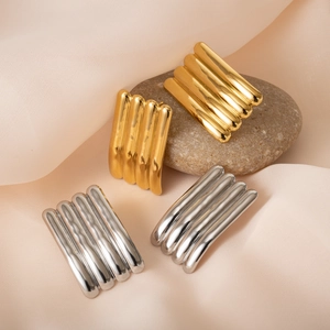Minimalist geometric gold and silver stripe tube earrings on silk background