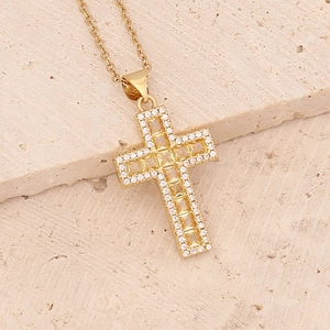Macro shot of gold cross necklace with micro-paved cubic zirconia on stone slab