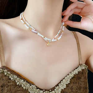 Detail of a double-layered faux pearl beaded necklace with gold pendant on woman neck
