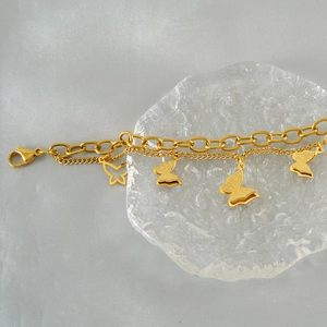 Detail of gold double-layered butterfly bracelet with matte and hollow pendants
